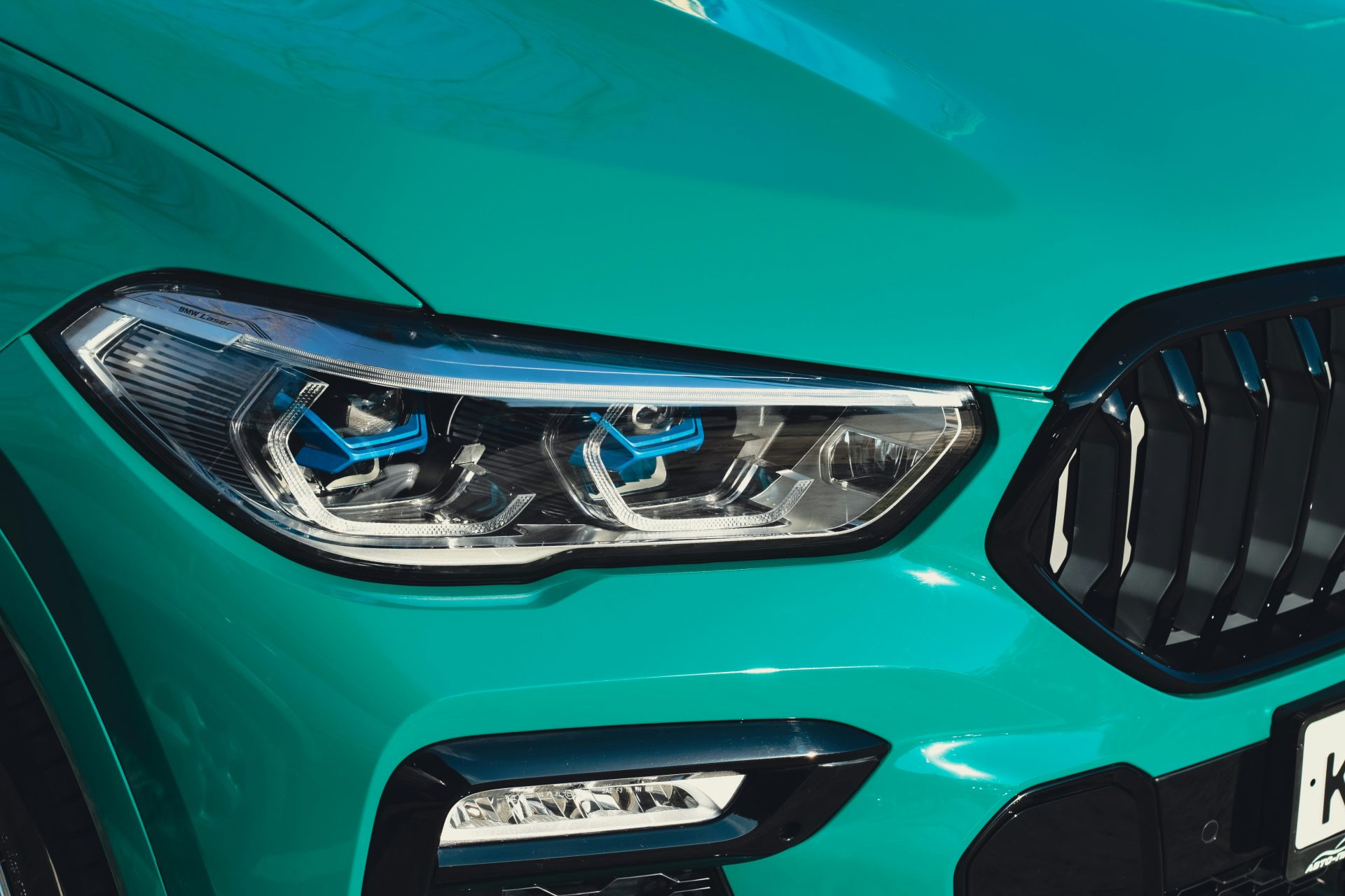 a close up of the front of a green bmw suv